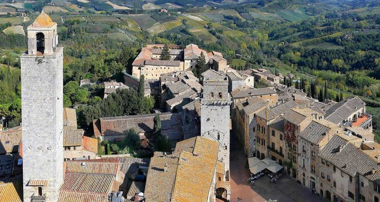 Perspective aérienne des tours de pierre médiévales de San Gimignano s'élevant de la campagne toscane vallonnée.