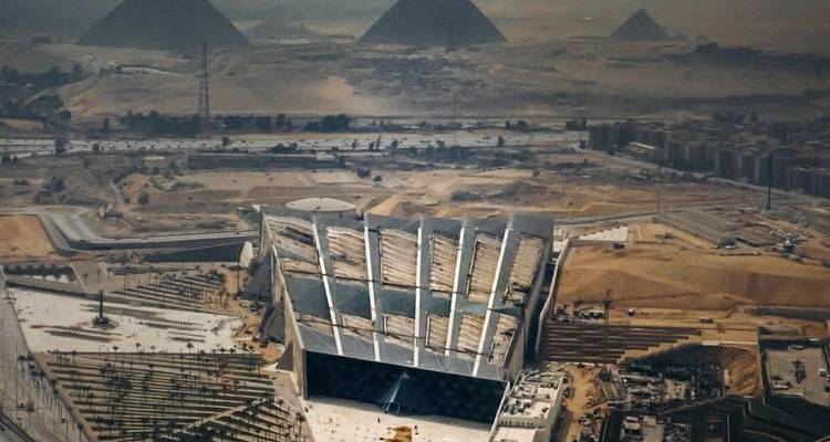 Vue aérienne du Grand Musée égyptien avec les pyramides s'élevant dans le désert au-delà.