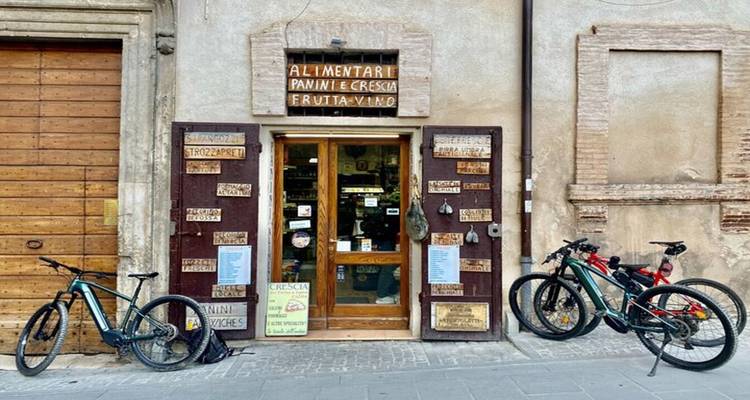 Rustic grocery storefront with handwritten signs and parked bicycles leaning on the wall.