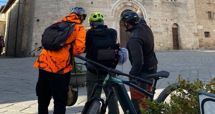 Cyclists review a map beside their bikes in front of a stone church entrance.