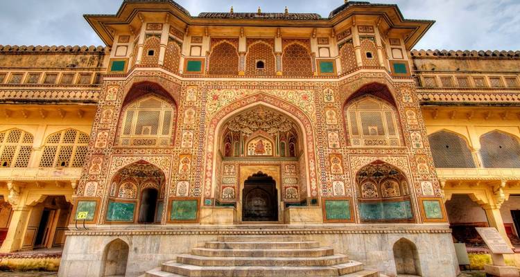 Richly ornamented gateway of Amber Fort with detailed frescoes, arches and marble stairway.