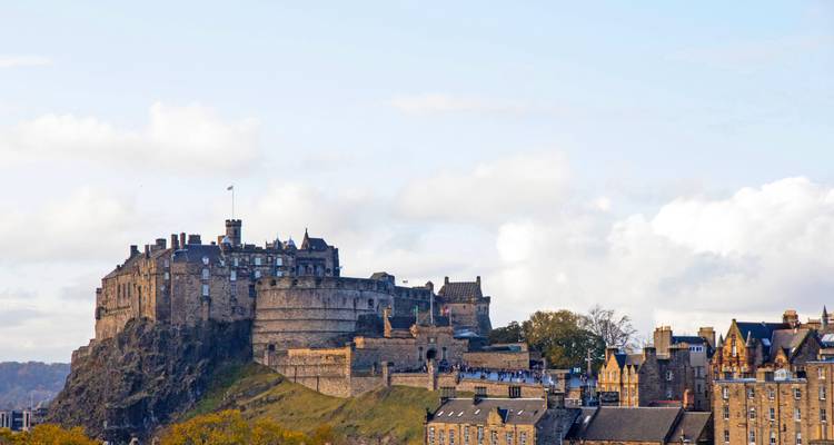 Edinburgh Castle dominates its rocky crag above the city’s historic skyline under a pale blue sky.