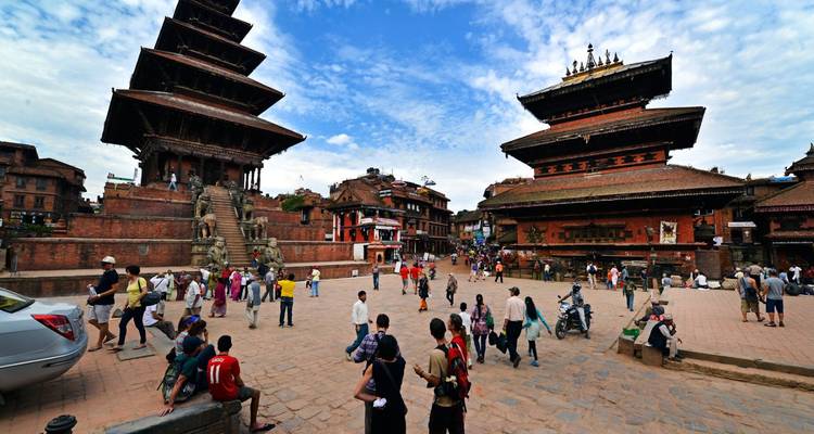 Wide plaza of Bhaktapur with visitors exploring its towering pagoda temples under blue skies.