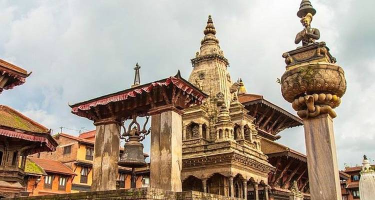Historic stone temples and ceremonial bell of Bhaktapur under dramatic skies.
