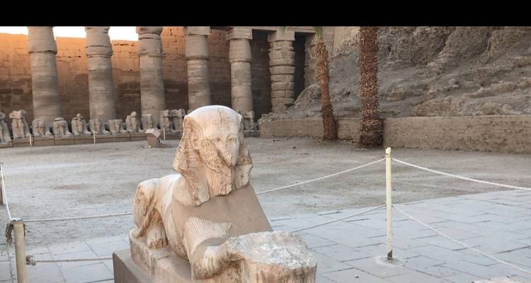 Small sphinx statue in a sparse courtyard of an ancient temple complex at dusk