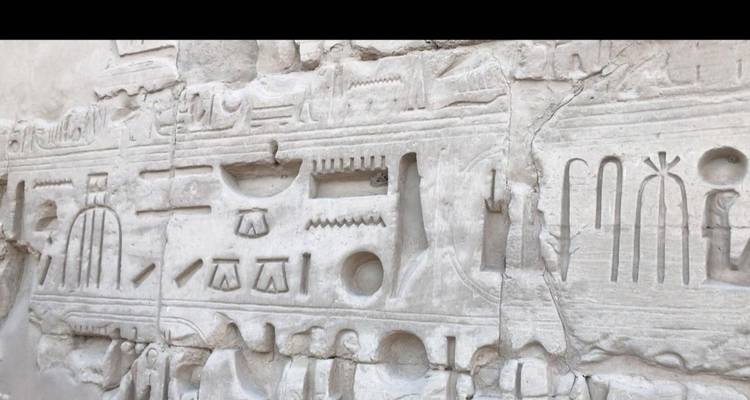 Weathered pale relief carving of hieroglyphic symbols and objects on a temple wall