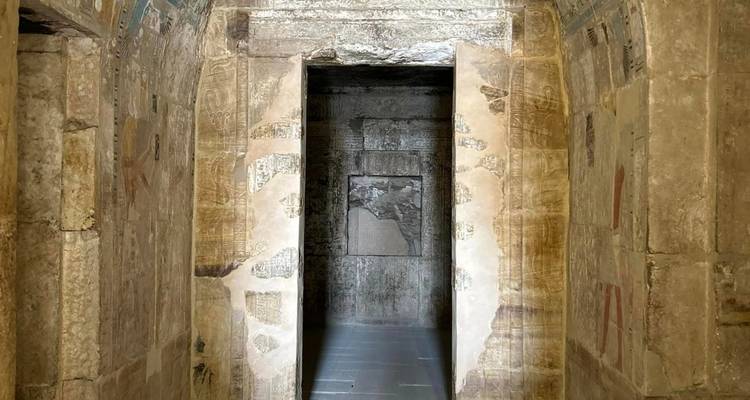 Stone entrance corridor of an ancient tomb decorated with faded carvings and hieroglyphs