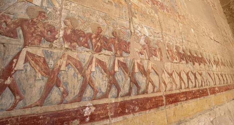 Relief wall showing a procession of painted ancient Egyptian figures in red and blue tones