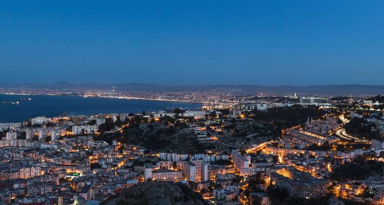 Evening panorama of Algiers city lights stretching along the Mediterranean coast.