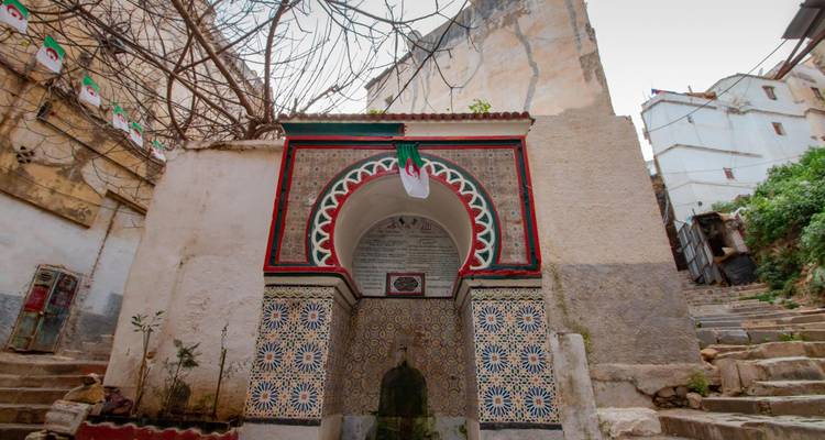 Ornate tiled fountain with decorative archway in a narrow historic alley