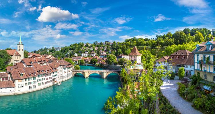 Panoramic view of Bern’s turquoise Aare River, stone bridge and red-roofed old town under a blue sky
