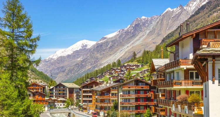 Charming alpine village with wooden chalets nestled beneath high snow-tipped mountains