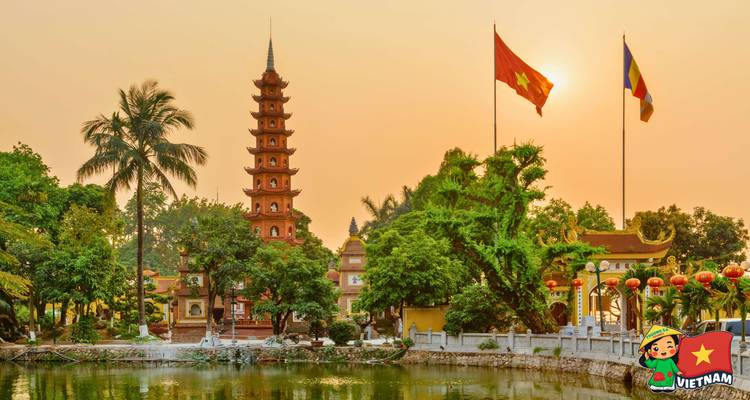 Tran Quoc Pagoda omlijst door palmen en vlaggen die weerspiegelen in een meer tijdens een warme zonsonderganggloed.