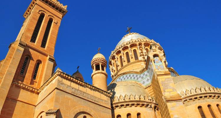 Gouden koepels en torens van Notre-Dame d'Afrique glanzen tegen een diepblauwe hemel.