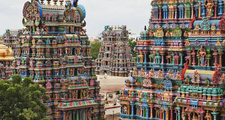 Die lebhaft bemalten Gopurams eines südindischen Hindu-Tempels ragen über die Stadtlandschaft auf.