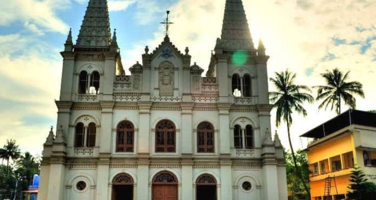 Basilika aus der Kolonialzeit mit Doppeltürmen, die sich gegen die helle Sonne und Palmen abzeichnen.