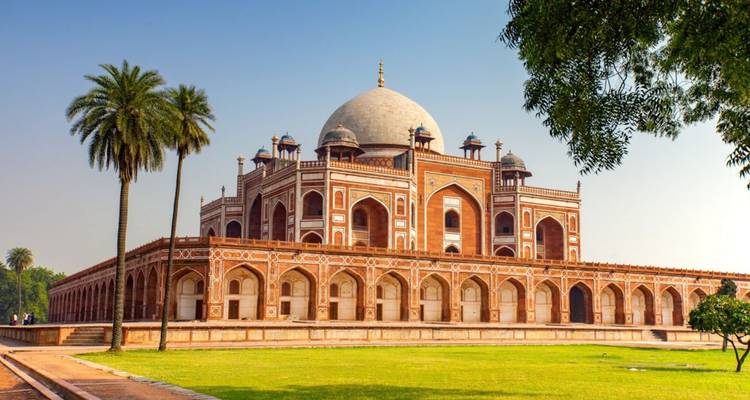 Humayuns Grab in Delhi, umrahmt von üppigem Grün und einer einzelnen Palme unter klarem Himmel.