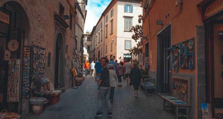 Narrow Italian alley with locals and tourists browsing shops and ceramics.
