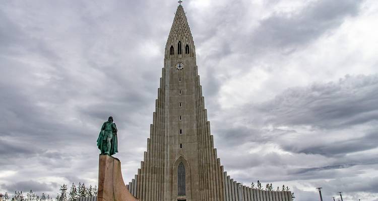 Der modernistische Turm der Hallgrímskirkja und die Explorerstatue ragen hoch unter düsteren isländischen Himmeln auf.