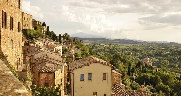 Les maisons de village toscan en terrasses dégringolant une pente et surplombant la campagne vallonnée au crépuscule