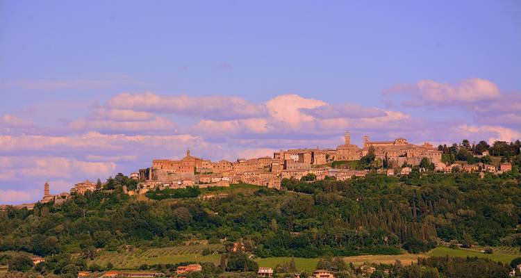 Vue lointaine d'une ville fortifiée sur une colline baignée de lumière chaude contre un ciel pourpre