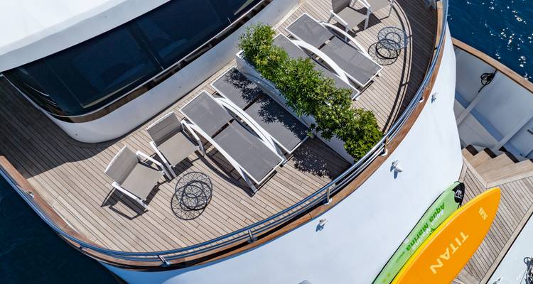 Overhead shot of sun loungers and greenery on the yacht's bow deck.