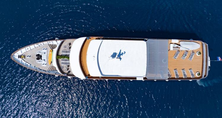 Top-down aerial of the yacht showing full deck layout cruising through deep blue water.