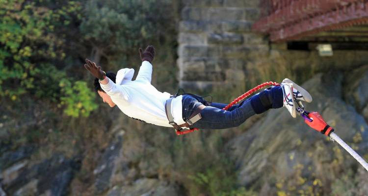 Adventurer leaps off a bridge in a harness during an exhilarating bungy jump over a rocky gorge.