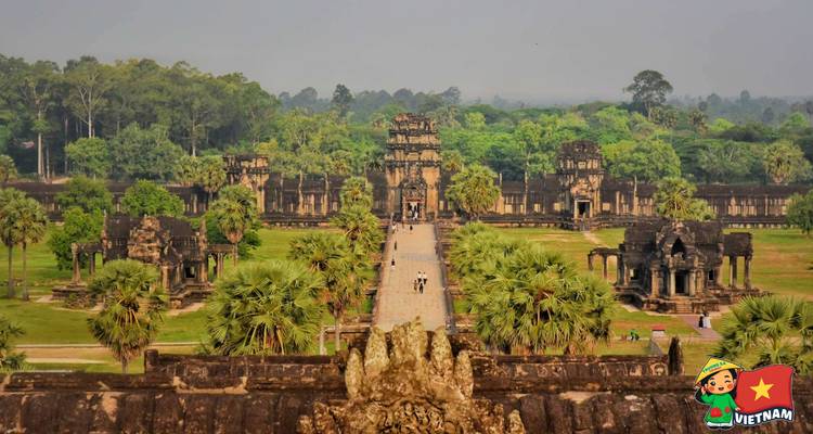 High vantage view down the main sandstone causeway leading into Angkor complex surrounded by green forest.