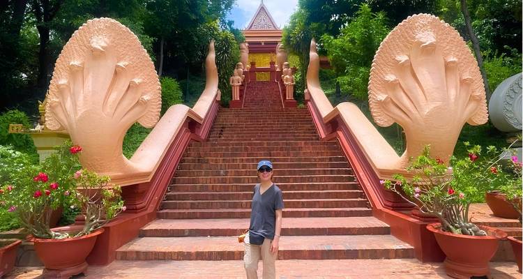 Traveller stands before grand staircase flanked by twin naga sculptures leading to a Buddhist shrine.