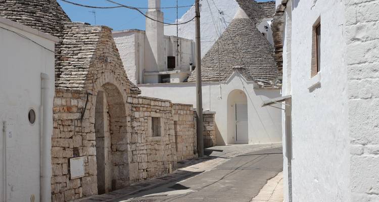 Ruelle étroite de maisons trulli traditionnelles blanchies à la chaux avec des toits coniques en pierre