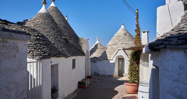 Ruelle tranquille bordée de maisons trulli coniques sous un ciel bleu éclatant
