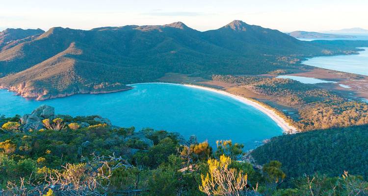 Aerial view of the pristine crescent-shaped Wineglass Bay surrounded by forested mountains