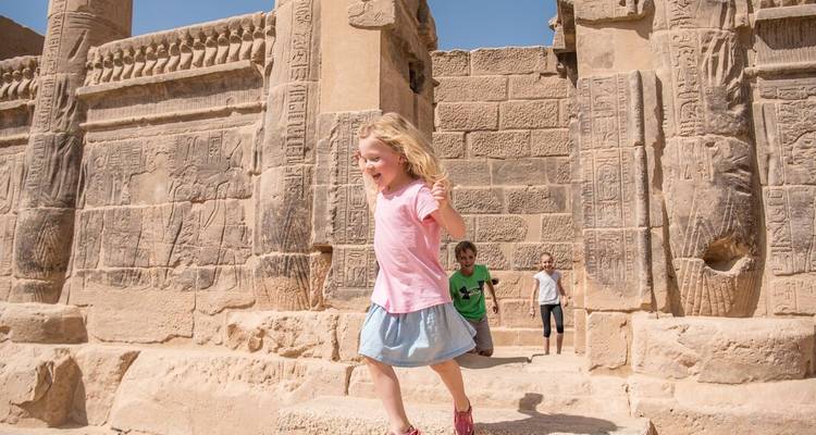 Des enfants courant joyeusement à l'intérieur des murs de pierre anciens d'un temple égyptien.