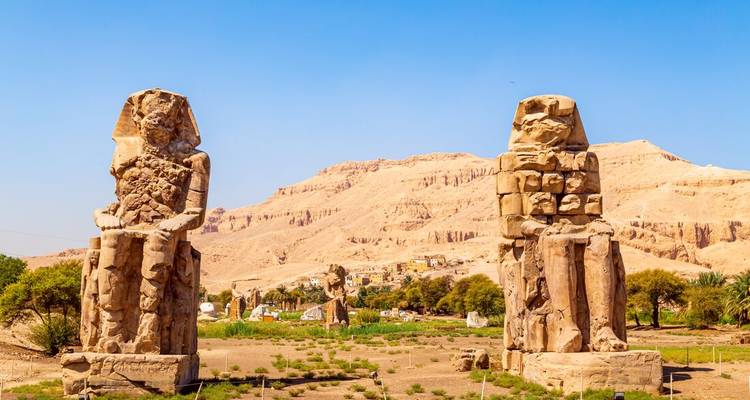 Les deux colosses jumeaux de Memnon se dressant majestueusement dans un paysage désertique sous un ciel dégagé.