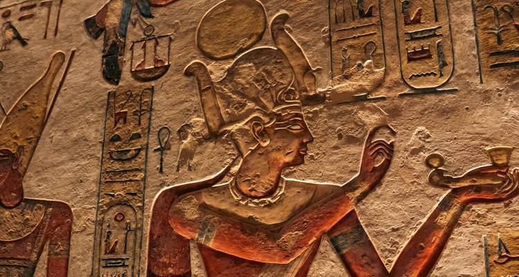 Detailed close-up of carved and painted pharaonic reliefs on a temple wall.