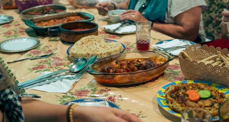 Traditional Egyptian meal served family-style on a patterned tablecloth with various dishes and drinks.