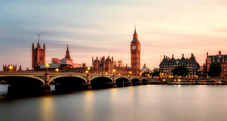 Twilight view of London’s Houses of Parliament and Big Ben beside Westminster Bridge reflecting in the Thames.