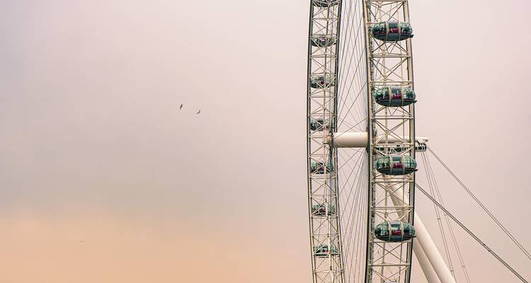 Minimalist close-up of the London Eye Ferris wheel cabins set against a pastel evening sky.