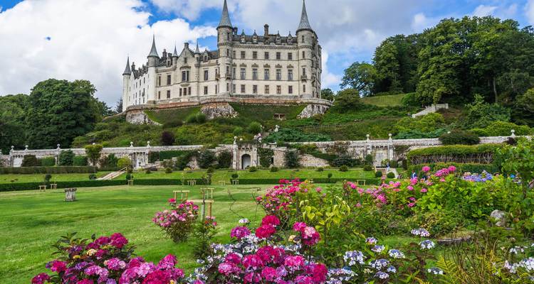 Elegant white-towered Dunrobin Castle framed by colorful flower gardens and lush trees