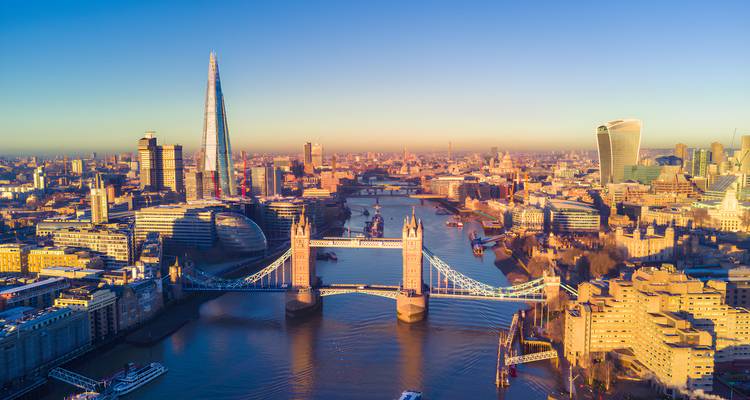 Goldener Sonnenaufgang über London mit der Tower Bridge und The Shard, die warmes Licht auf der Themse reflektieren