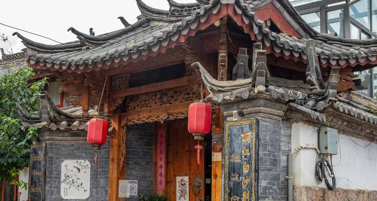 Traditional tiled-roof courtyard gate decorated with red lanterns in Lijiang old town.