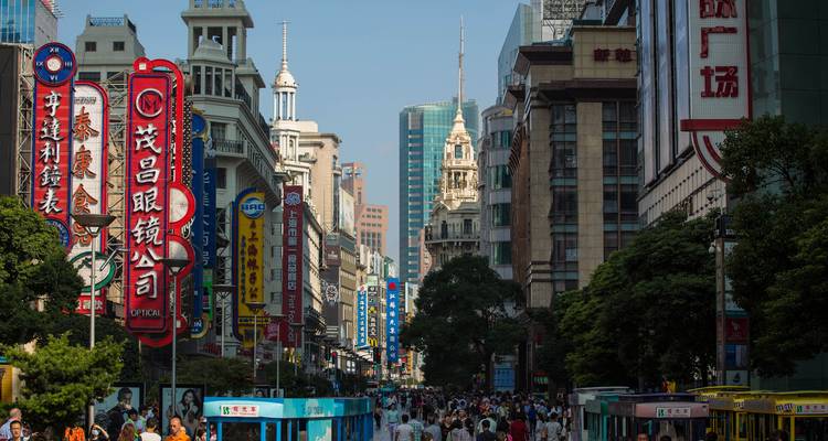 Belebte Fußgängerzone für Einkäufe in Shanghai, gesäumt von hohen Neonzeichen, historischen Gebäuden und Menschenmengen