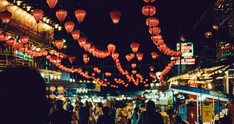 Un mercado nocturno vietnamita bullicioso brilla con hileras de linternas rojas y puestos abarrotados.