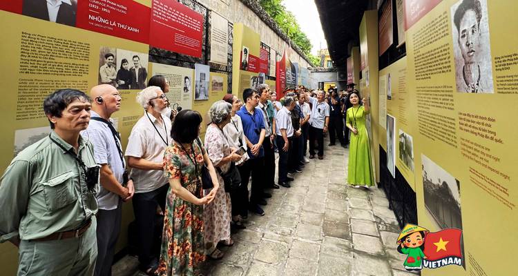 Large tour group listening to a guide inside an exhibit hall with information panels