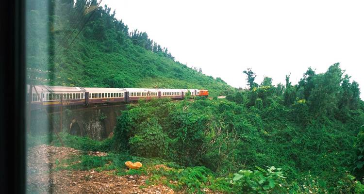 View from train window of carriages crossing a forested valley on a stone bridge