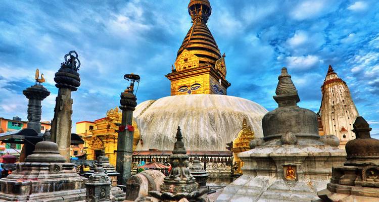 Levendige Swayambhunath-stupa met Boeddha-ogen omringd door stenen heiligdommen onder een dramatische hemel.