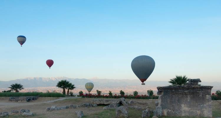 Des ballons à air chaud à différentes altitudes au-dessus de la campagne dégagée avec des montagnes lointaines.