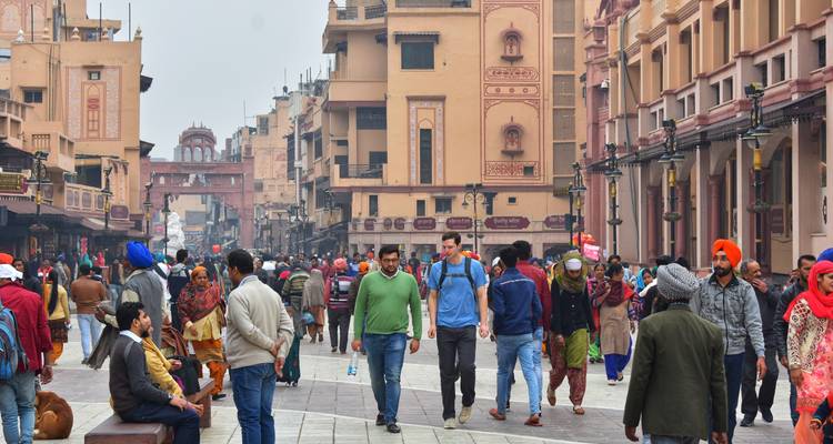 Bustling pedestrian street in Amritsar lined with pastel heritage buildings and shoppers in winter clothing.