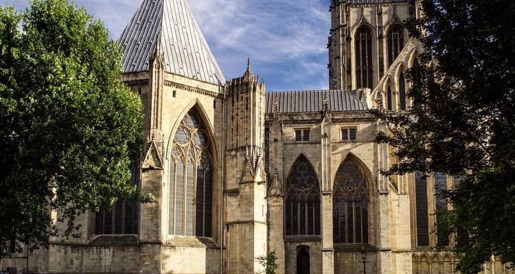 Les tours gothiques et les grands vitraux de la Cathédrale d'York s'élèvent majestueusement contre un ciel bleu dégagé.